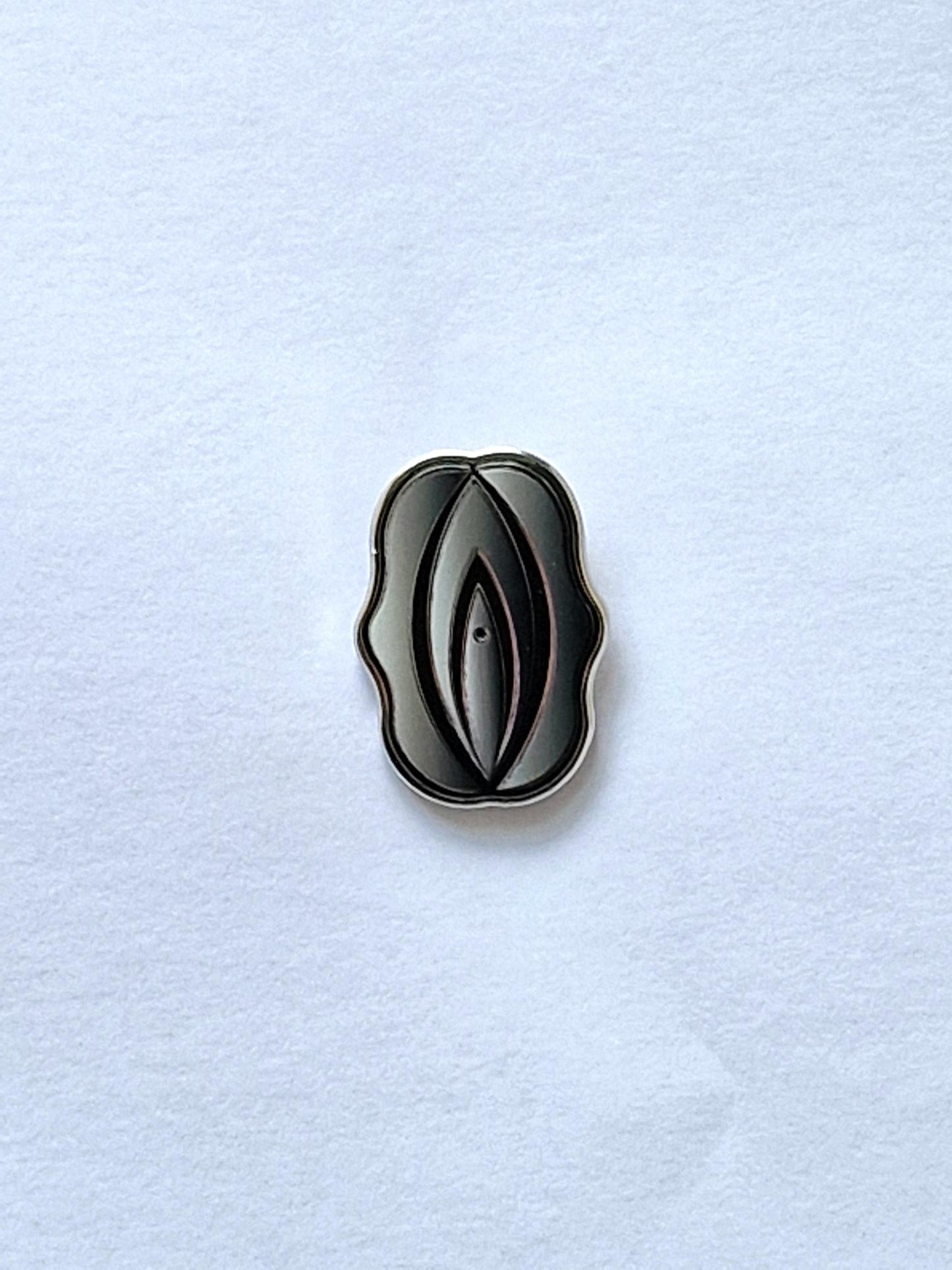 Divertido y diferente pin con forma de fifi plateado y negro.