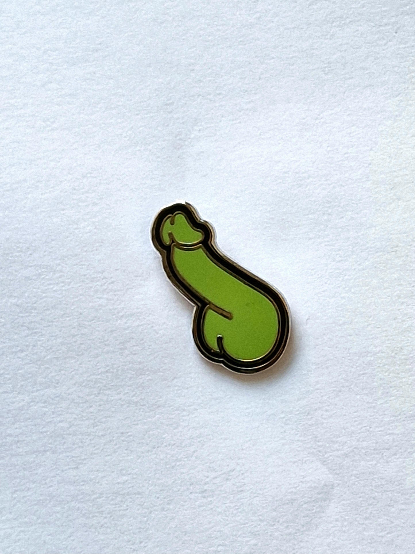 Un pin divertido y diferente con forma de pene verde y negro.