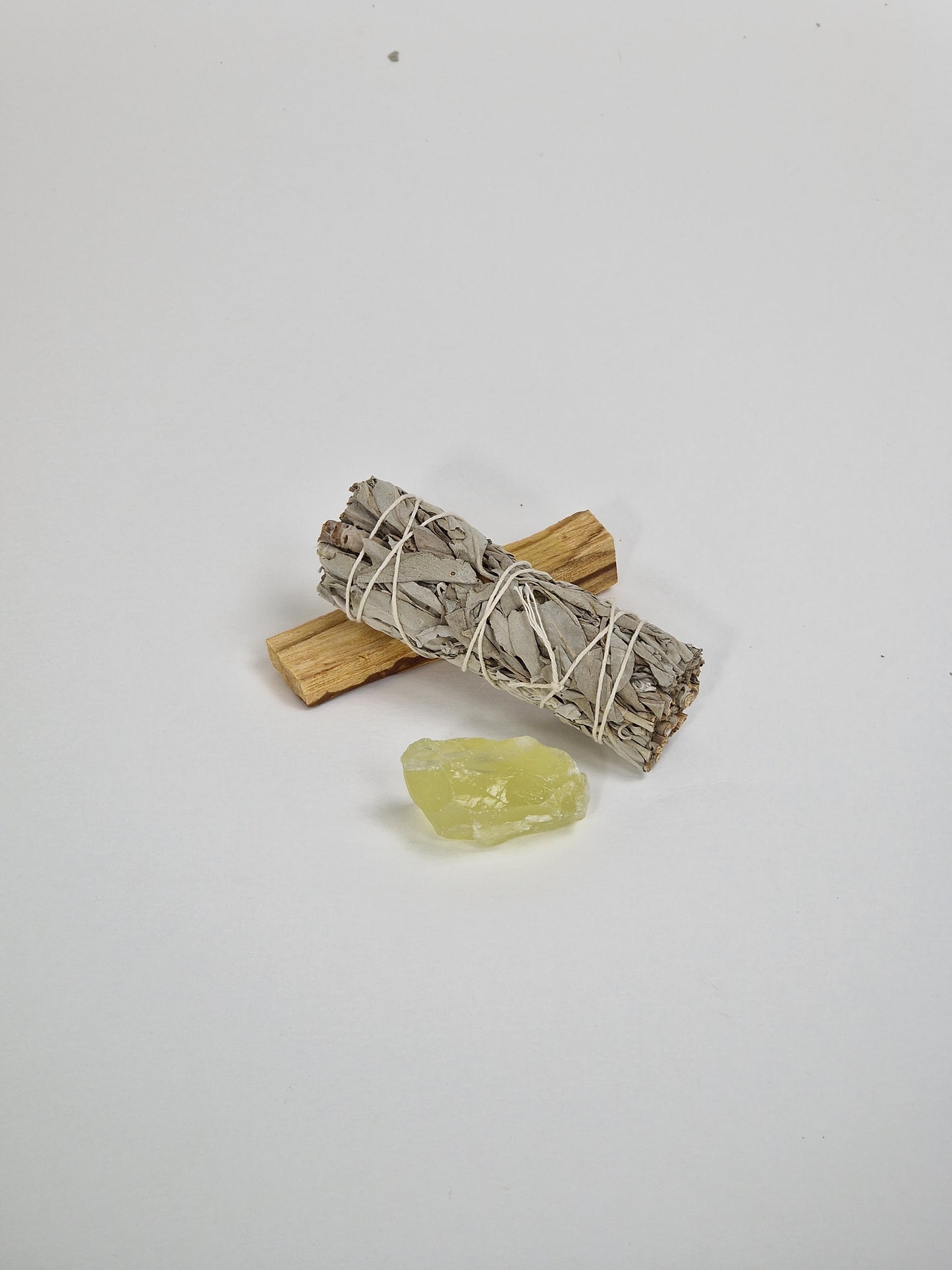 Ein Paket mit einem rohen Citrinkristall, einem großen Bündel Salbei und einem Stück Palo Santo, dem heiligen Holz