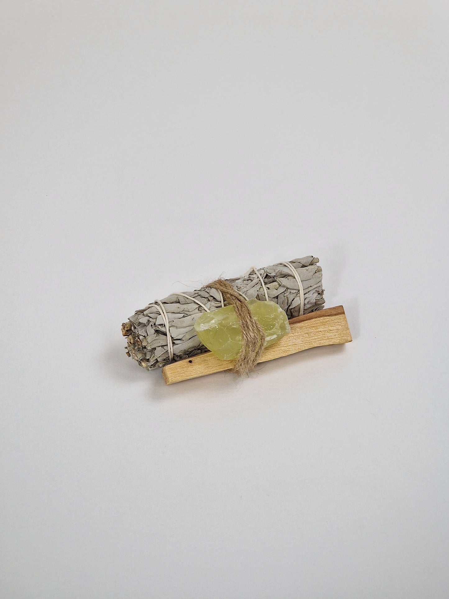 Ein Paket mit einem rohen Citrinkristall, einem großen Bündel Salbei und einem Stück Palo Santo, dem heiligen Holz