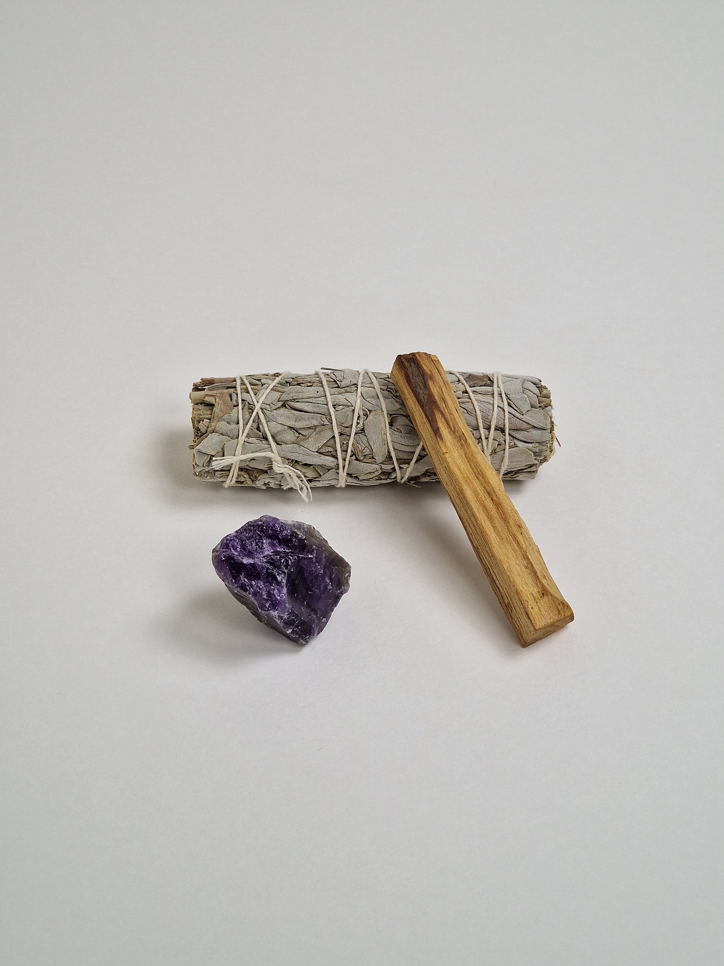 Cristal de amatista en bruto con un gran manojo de salvia blanca, un trozo de Palo Santo o madera sagrada