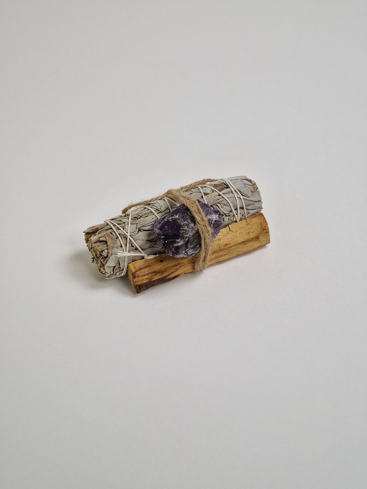 Cristal de amatista en bruto con un gran manojo de salvia blanca, un trozo de Palo Santo o madera sagrada