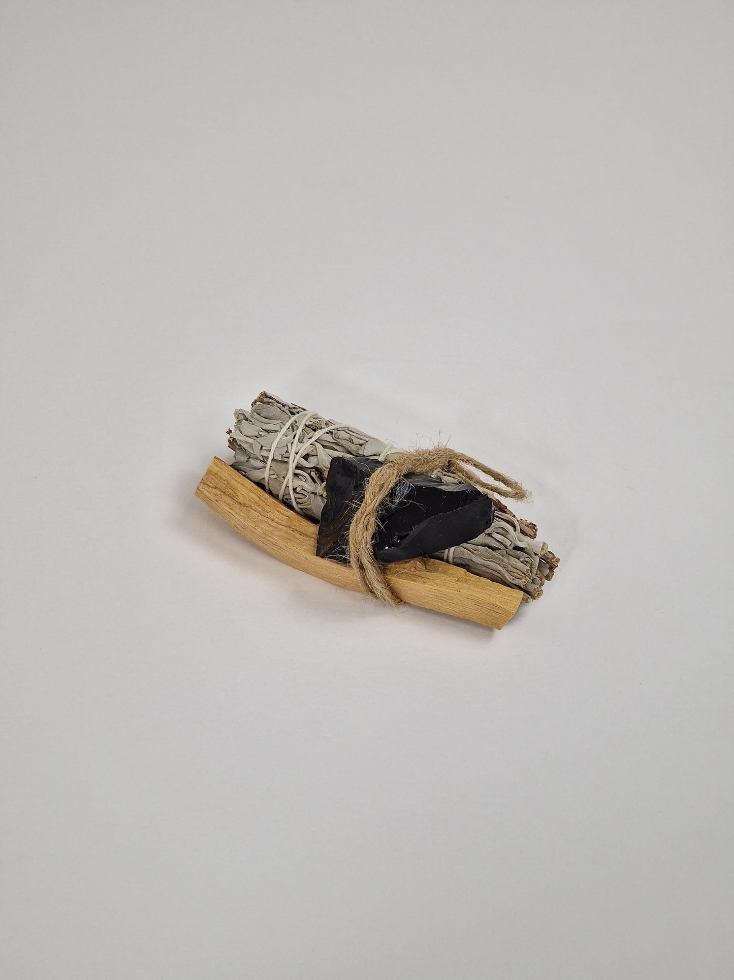 Paquete de ónix negro o cristal de ónix negro con un manojo grande de salvia blanca y un trozo de Palo Santo