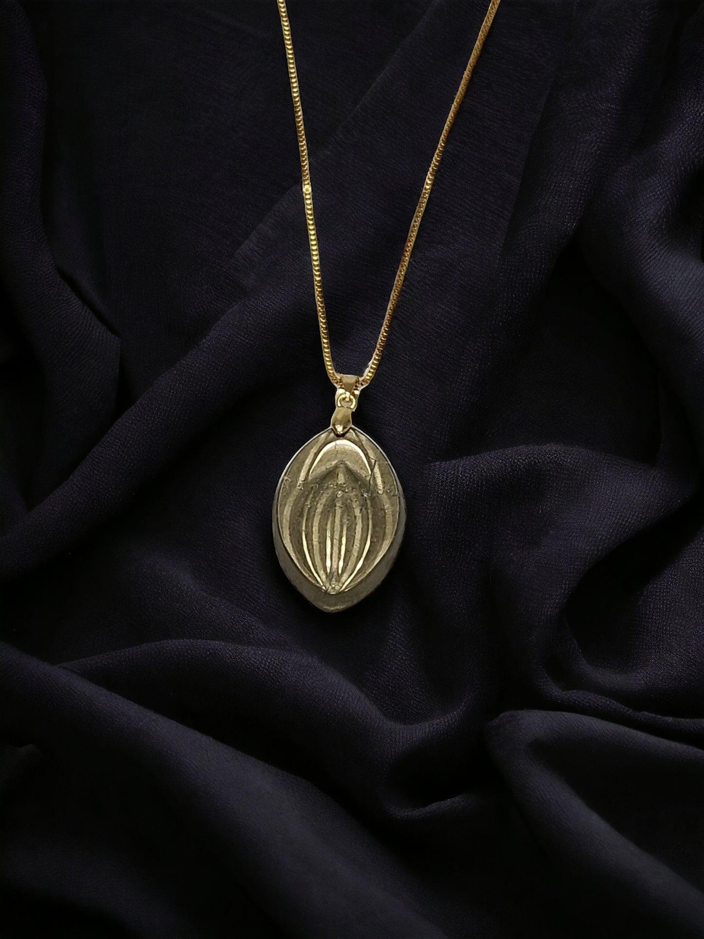 A beautiful necklace with a crystal of the stone pyrite, shaped like a vagina or fifi