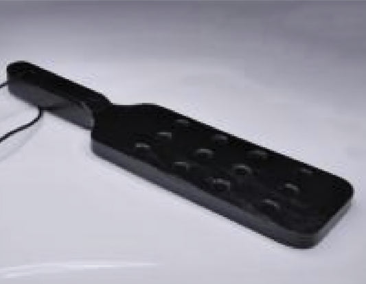 Paddel i svart trä med hål för bdsm lekar