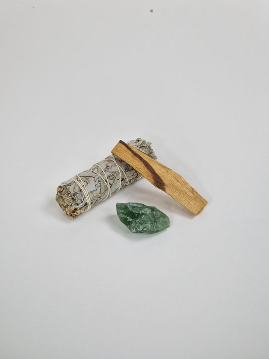 Un manojo grande de salvia blanca, un trozo de cristal crudo de fluorita verde, cristal de fluorita verde y un trozo de Palo Santo, madera sagrada